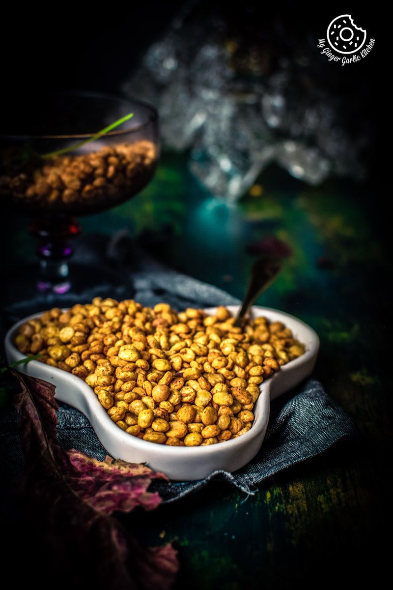 there is a bowl of chana dal namkeen on a table with a glass of wine