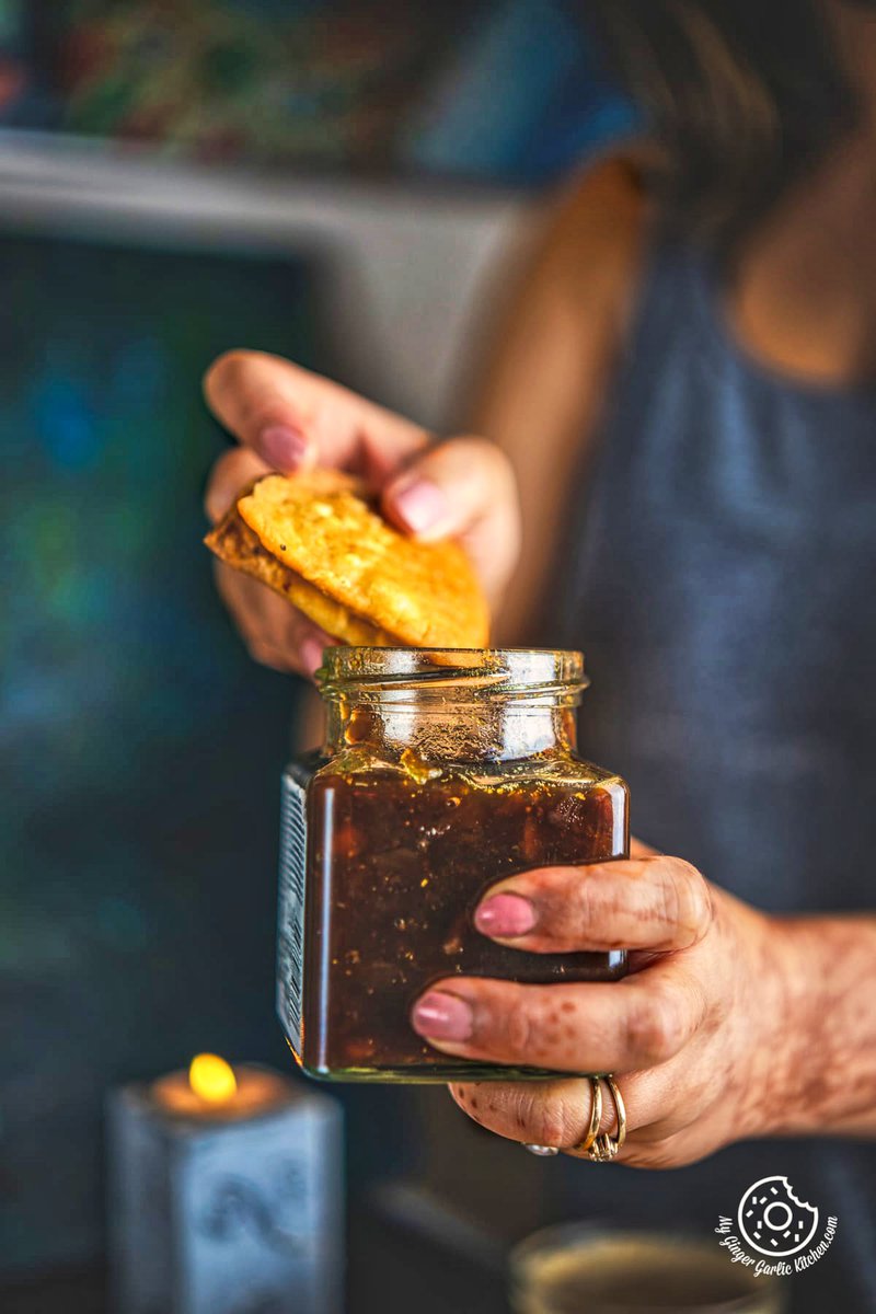 Image of Cheese Garlic Masala Mathri serevd in a bowl along with a cup of coffee and candles in background