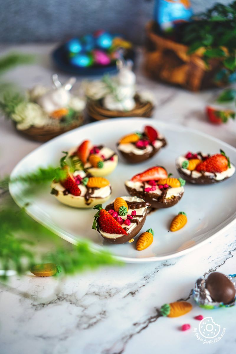 6 cheesecake filled easter eggs on a white plate with chocolate egg on the side