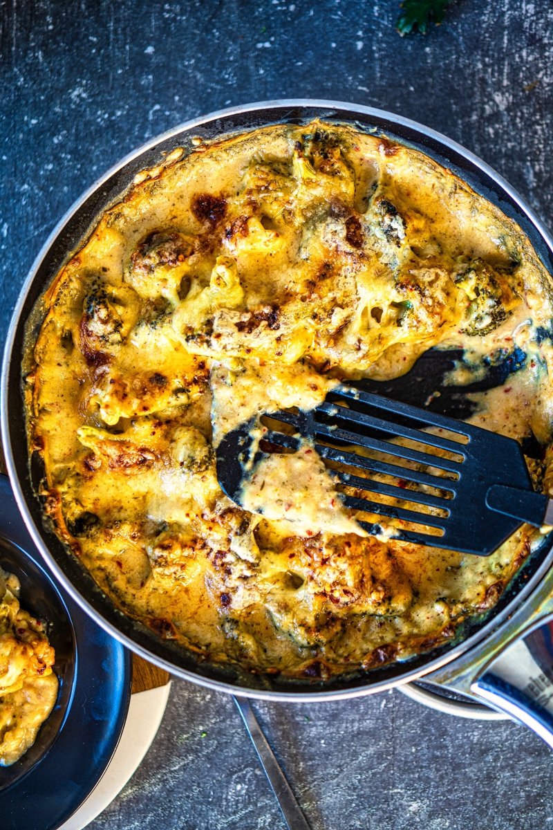 Cheesy broccoli casserole baked in a skillet with creamy garlic cheese sauce and golden, bubbly cheese