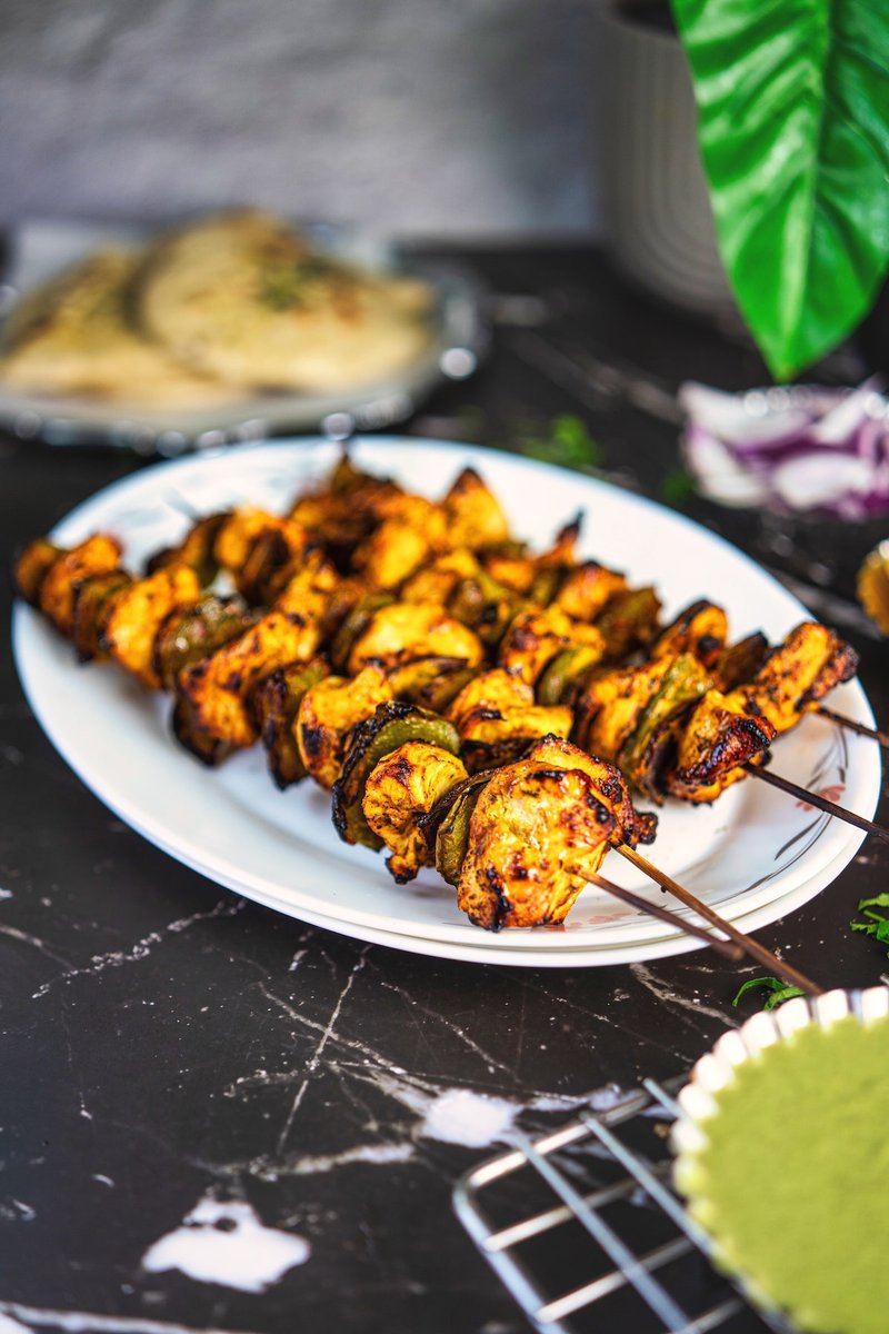Close-up of marinated chicken tikka kebabs arranged on metal skewers, ready for grilling over a barbecue