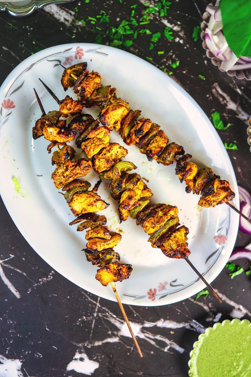 Chicken tikka kebabs garnished with lemon wedges, presenting a tantalizing sight of golden-brown grilled goodness, perfect for any gathering.