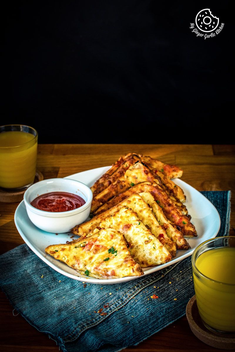 chilli cheese toast snack served in a white plate with some tomato ketchup