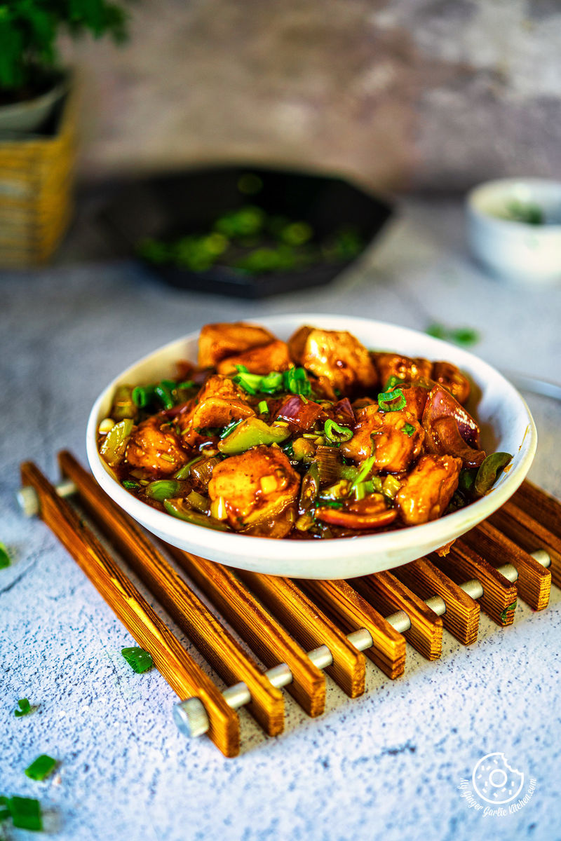 photo of a bowl of chilli paneer with chopsticks