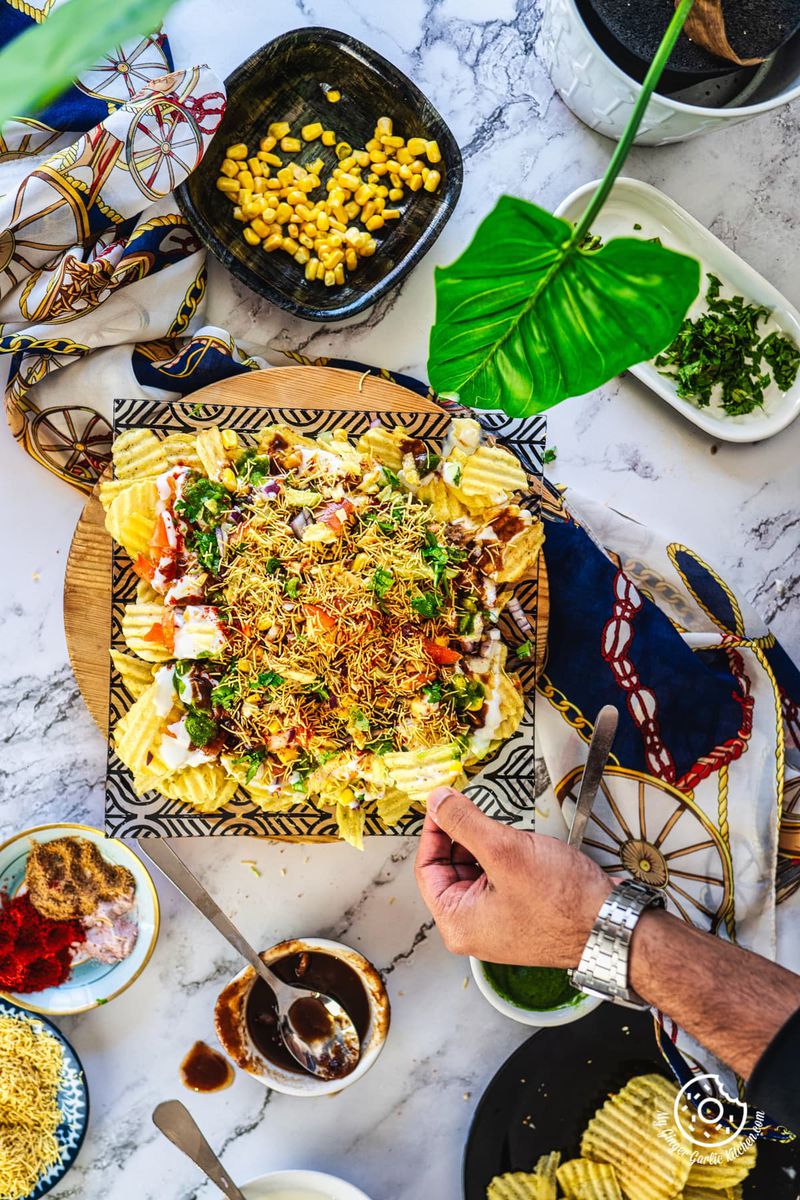 overhead shot of a hand holding chips from the chips chaat plate