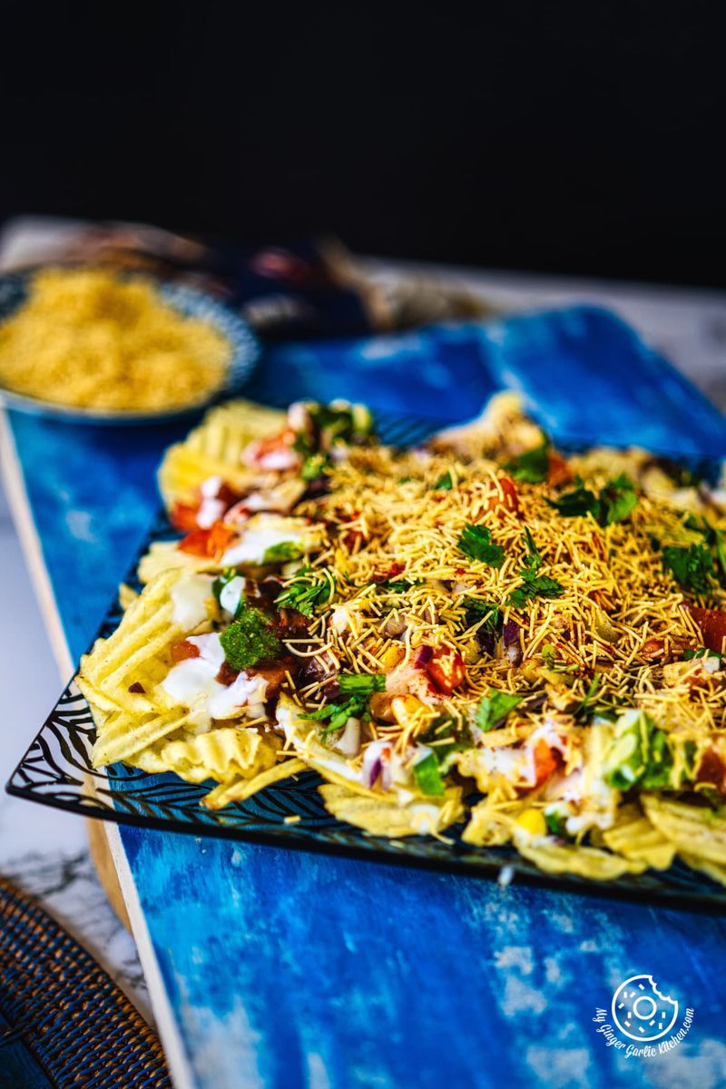 closeup shot of chips chaat served in a black and transparent plate