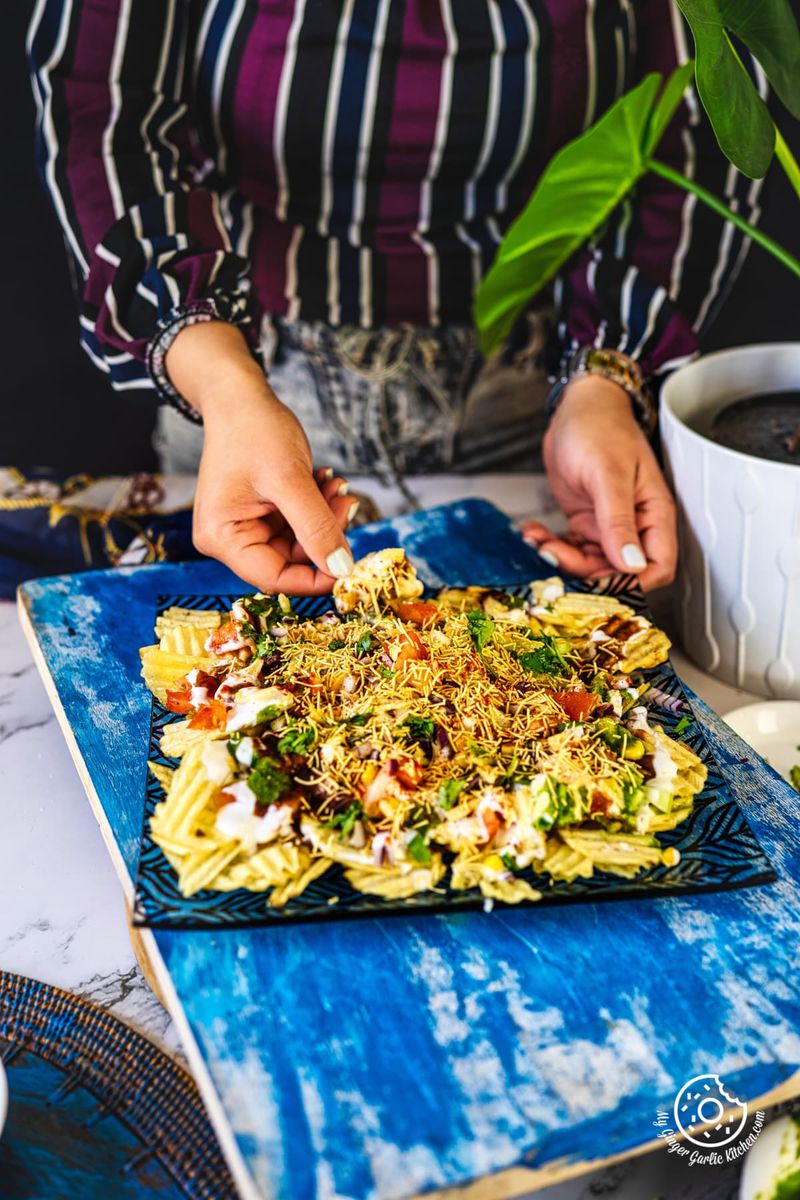 a female holding a chip from the chips chaat plate