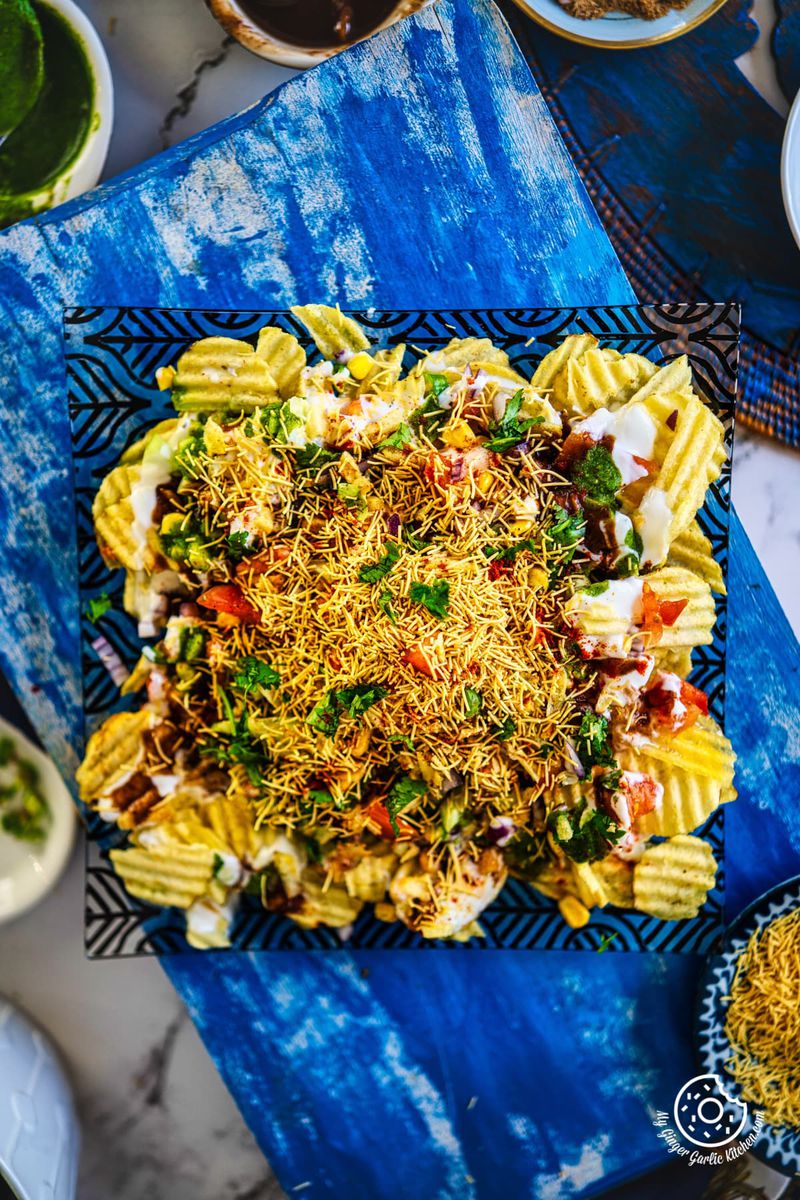 overhead closeup shot of chips chaat served in a black and transparent square plate