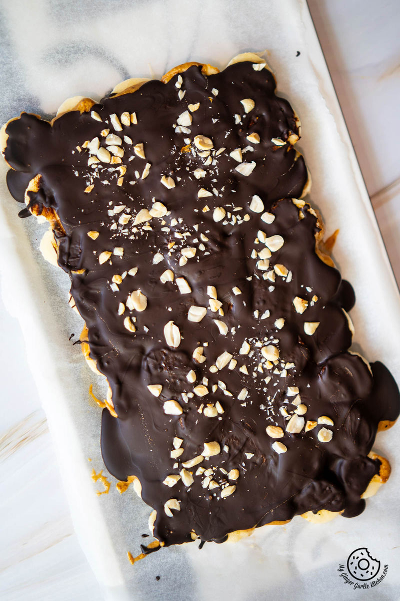 overhead photo of chocolate banana bark topped with roasted crushes peanuts on a white sheet of paper