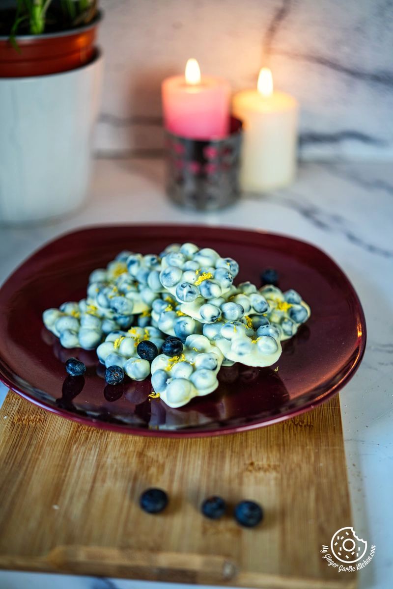 photo of a plate of chocolate covered blueberries on a cutting board
