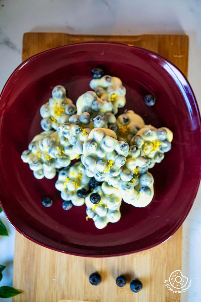 overhead photo of a red plate with chocolate covered blueberries on it 