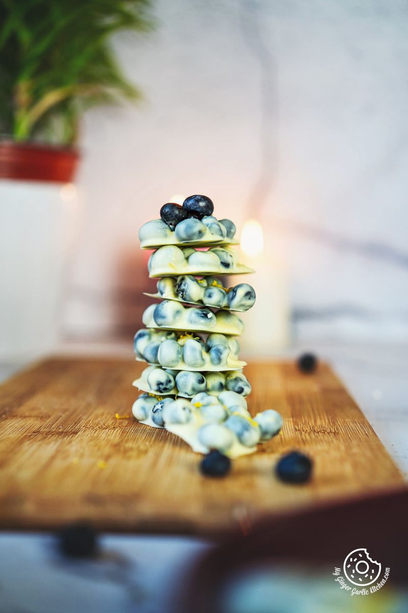 photo of a stack of white chocolate covered blueberries on a wooden cutting board