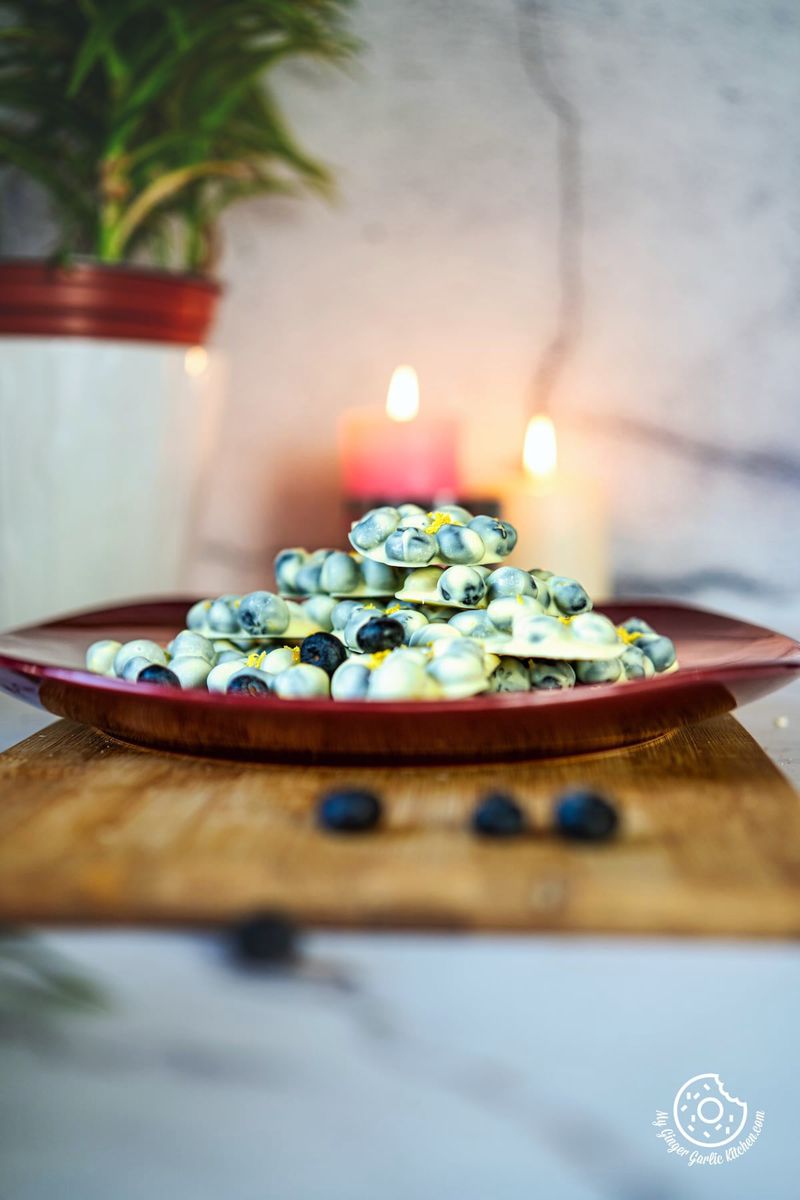 photo of a plate of  chocolate covered blueberries and a candle on a table