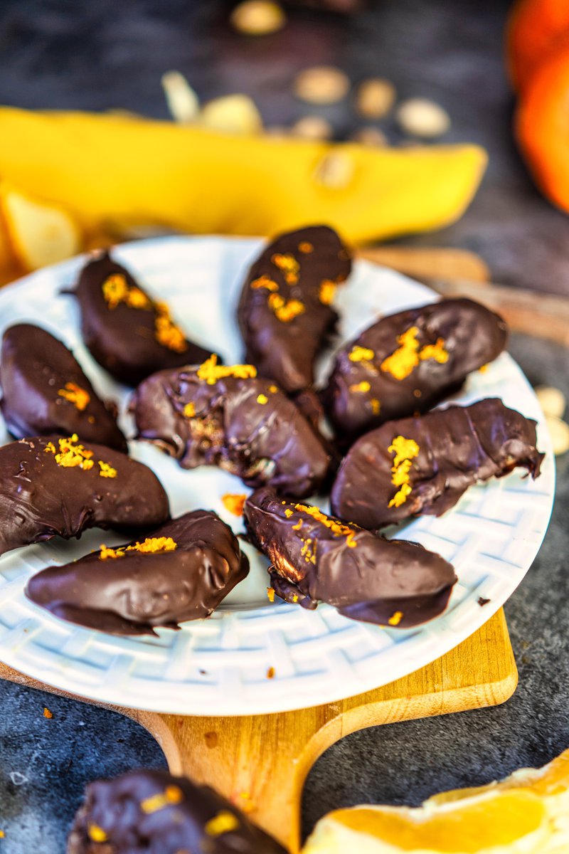 chocolate covered oranges on a plate with orange zest