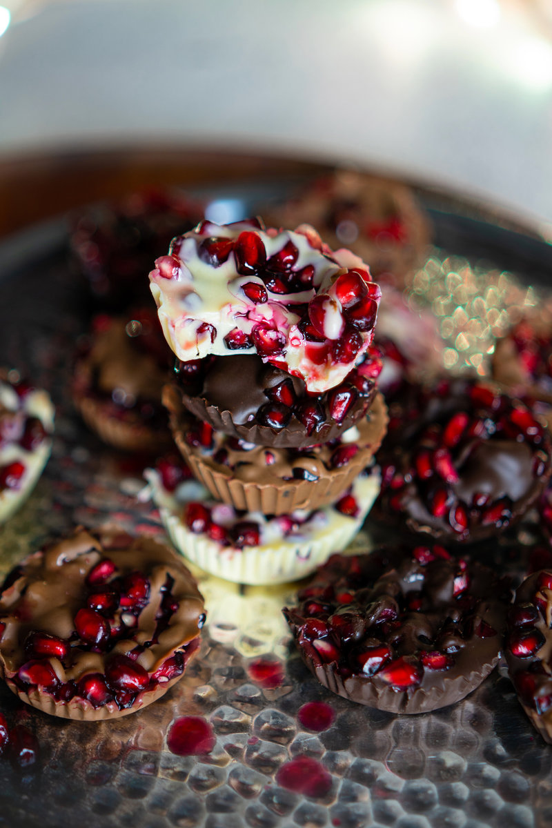  a lot of chocolate pomegranate bites on a plate with pomegranate