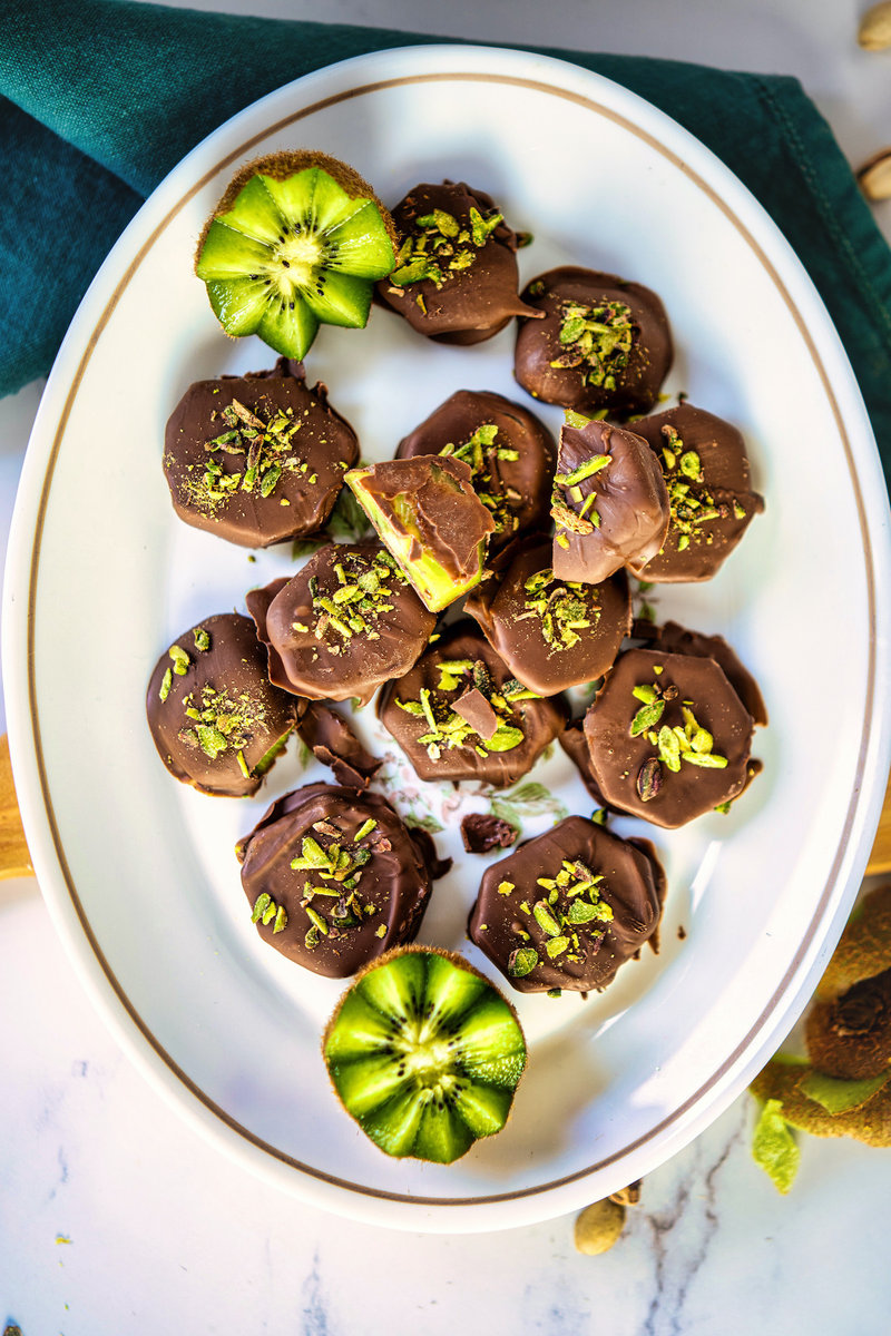 chocolate covered kiwifruit on a white plate on a table