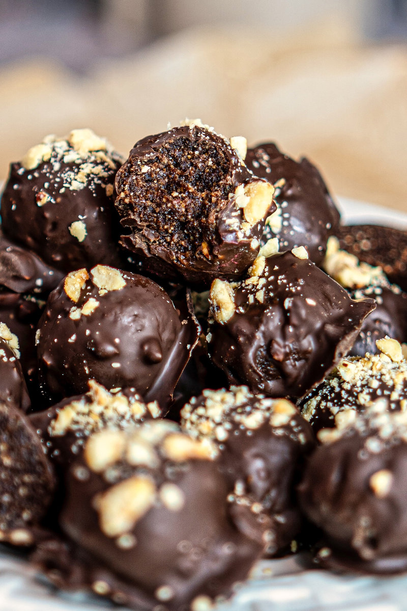 Close-up of chocolate hazelnut bliss balls topped with crushed nuts on a plate.