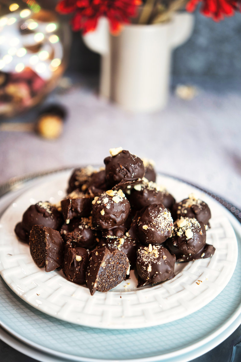 A plate of chocolate hazelnut bliss balls topped with crushed nuts.