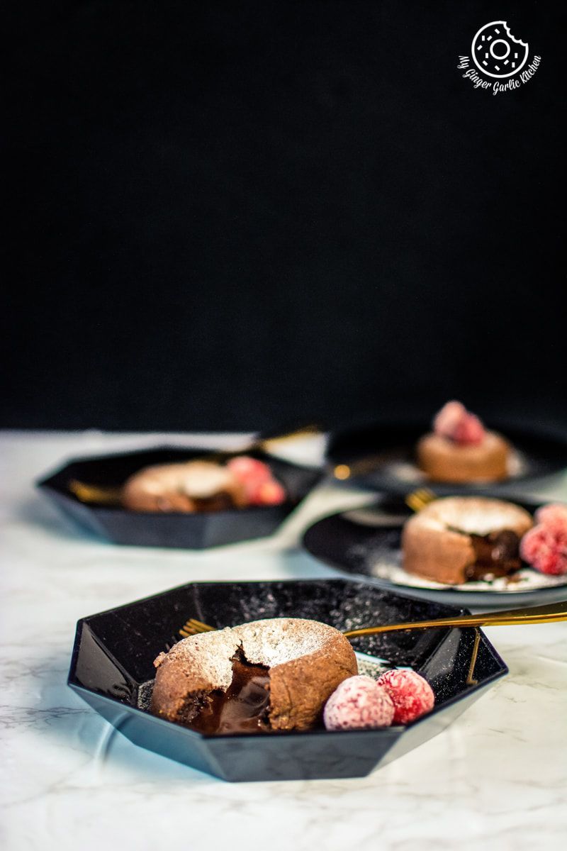 chocolate lava cake served in a black plate with strawberries
