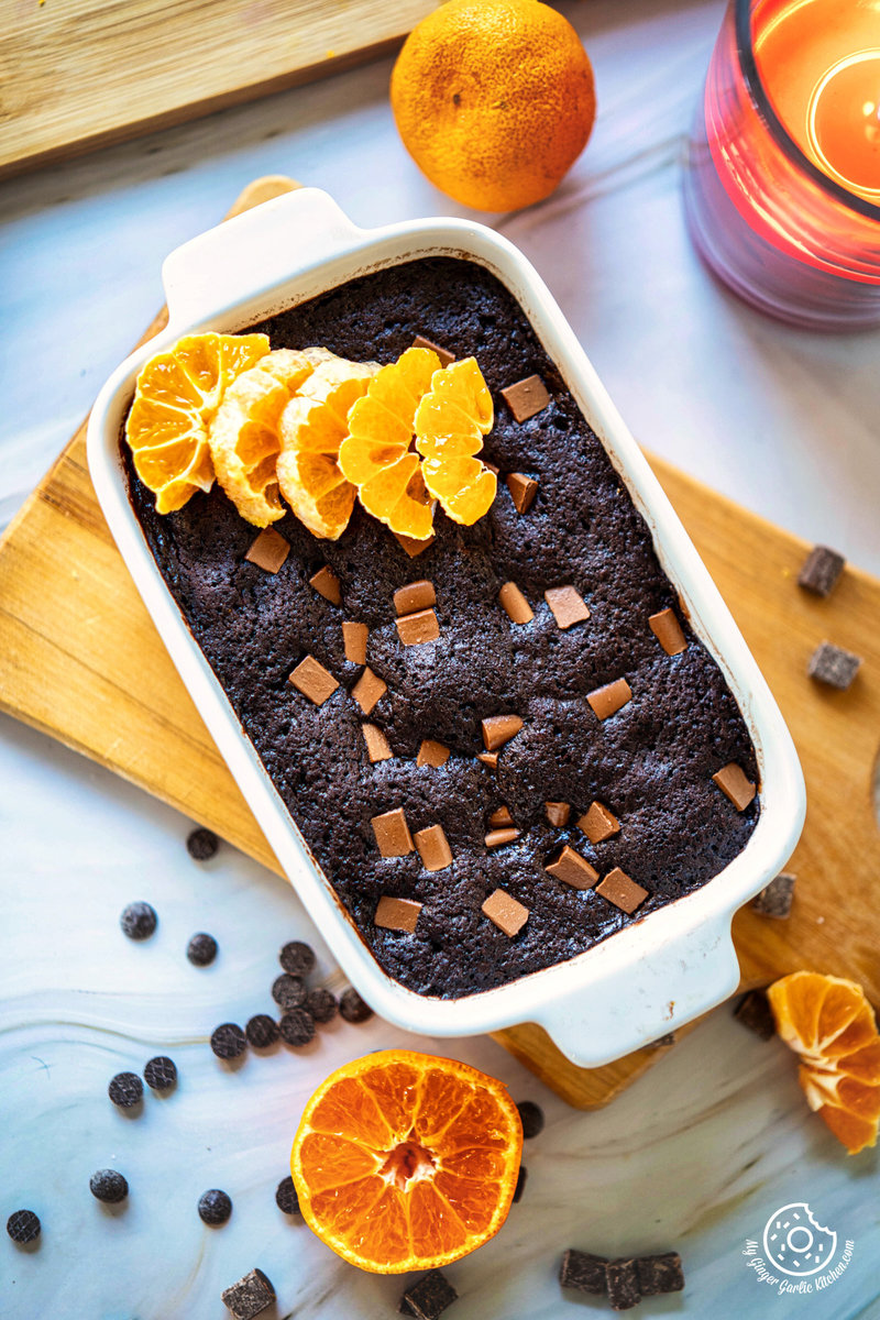 a chocolate orange mug cake in a baking dish with orange slices and chocolate chips