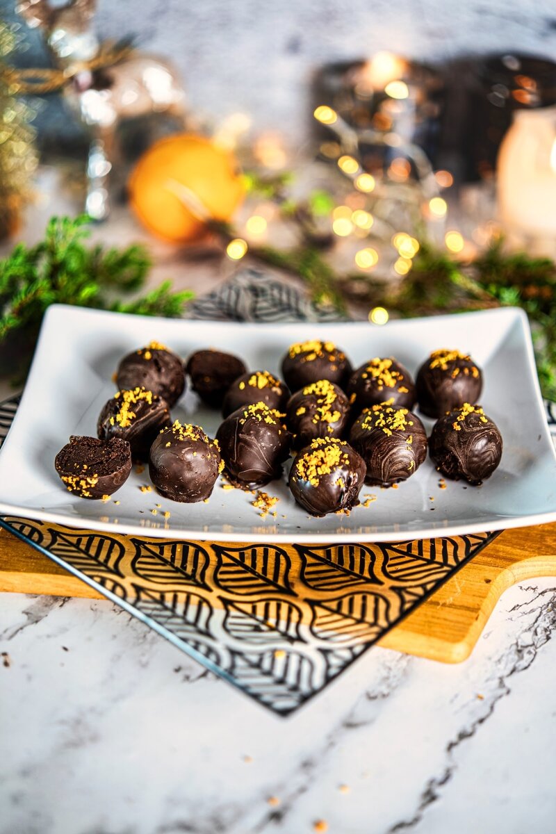 No bake vegan chocolate orange truffles served on a rectangular plate with orange zest garnish