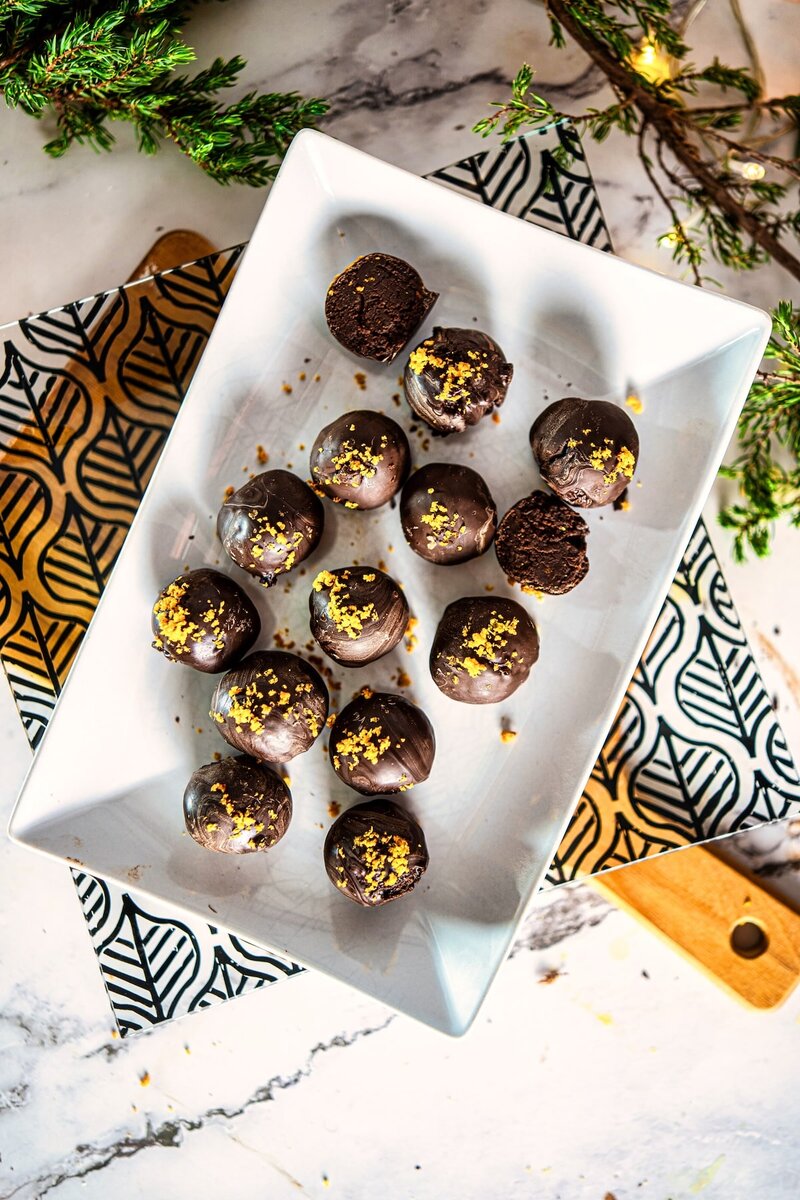 Top view of homemade vegan chocolate orange truffles arranged on a square plate with festive background