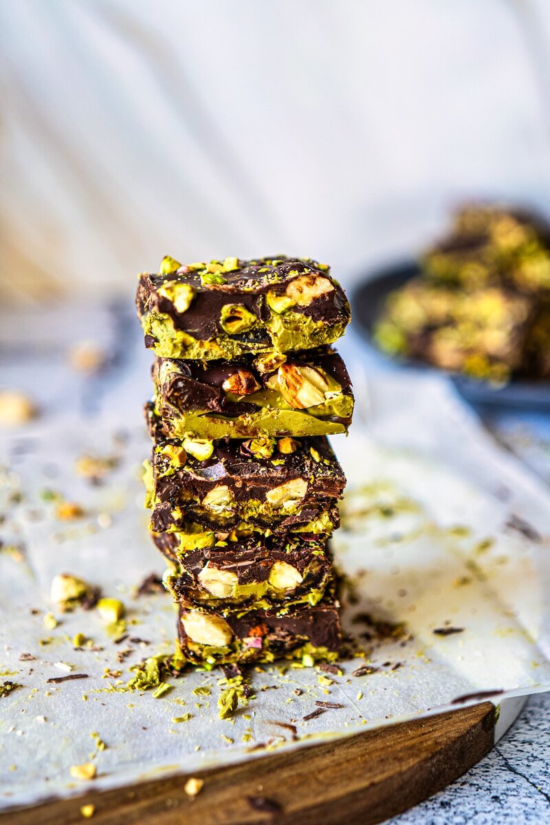 Stack of no bake chocolate pistachio date bars with visible layers of dates nuts and chocolate