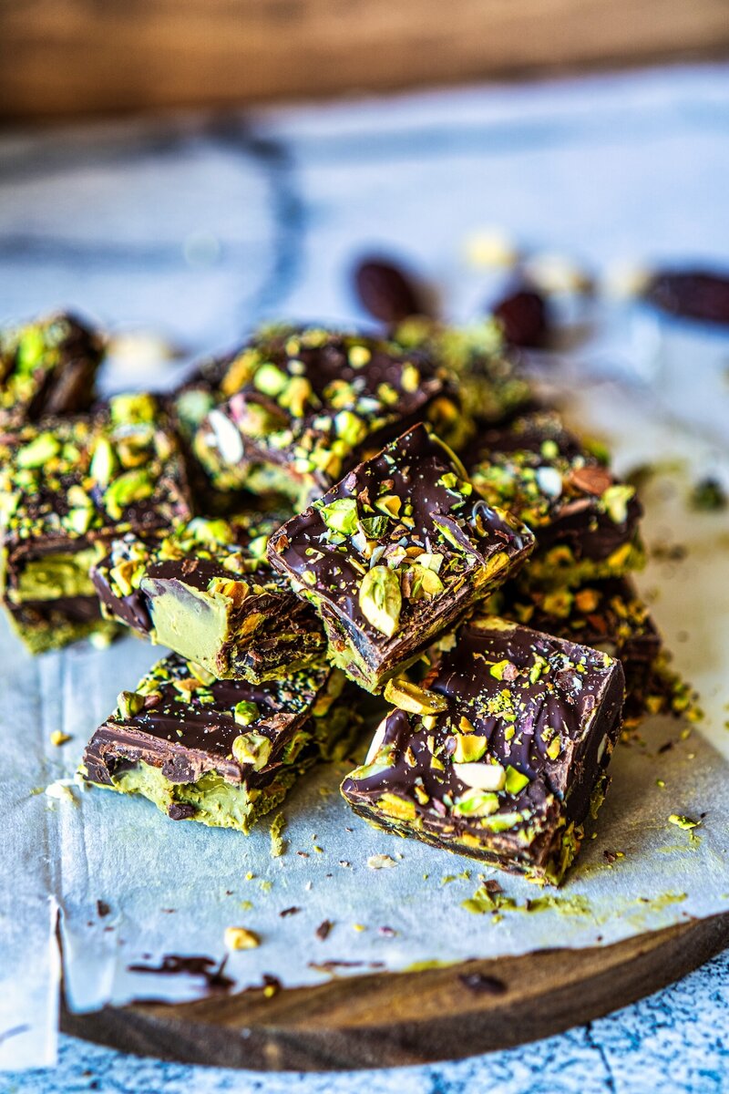 Stacked chocolate pistachio date bars with creamy pistachio layer and crunchy nuts close up
