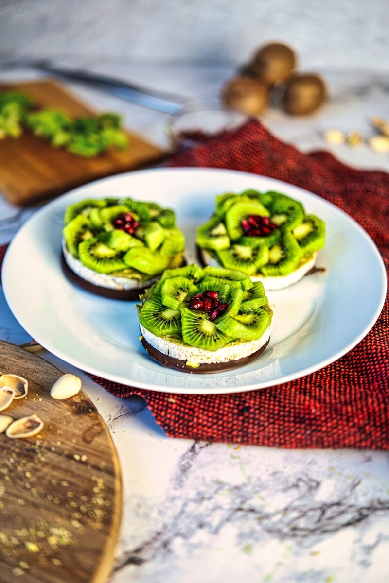Three Chocolate Pistachio Kiwi Rice Cakes on plate, easy no bake vegan rice cake dessert with dark chocolate and fresh kiwi