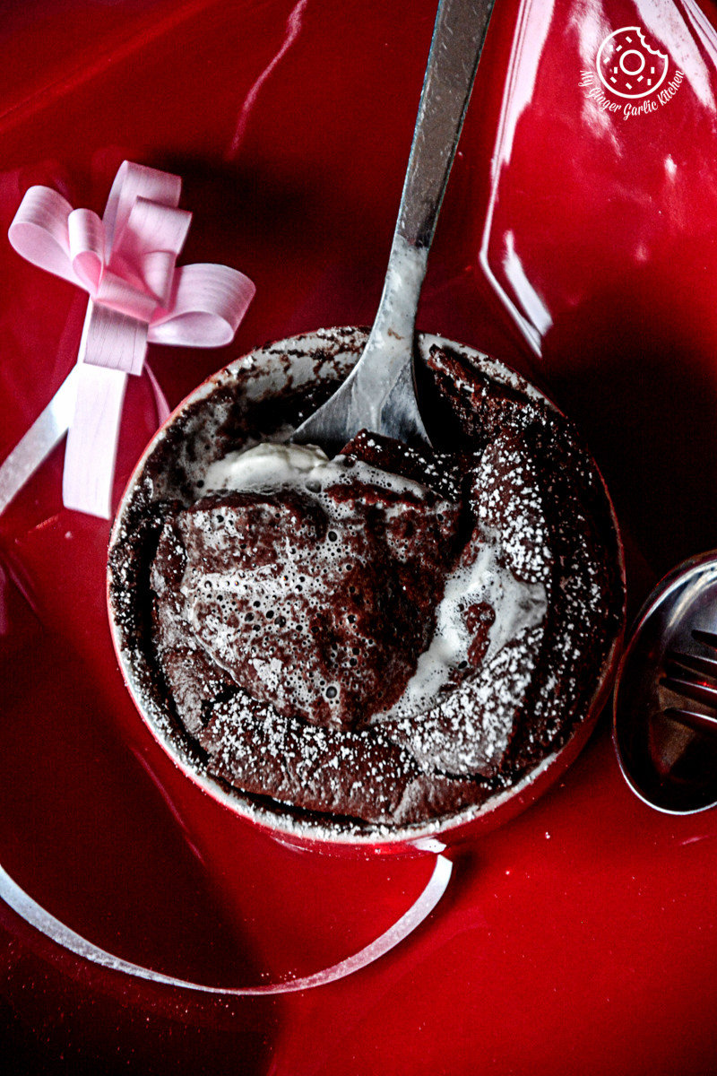 a red plate with a chocolate souffle and a spoon on it