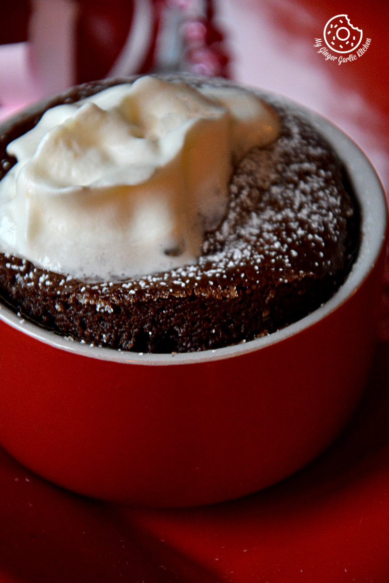 a small red bowl with a chocolate souffle and whipped cream