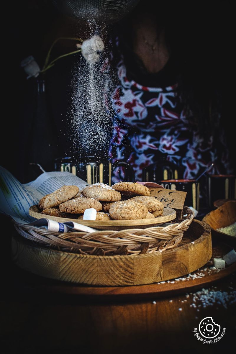 a female sprinkling sugar on coconut cookies