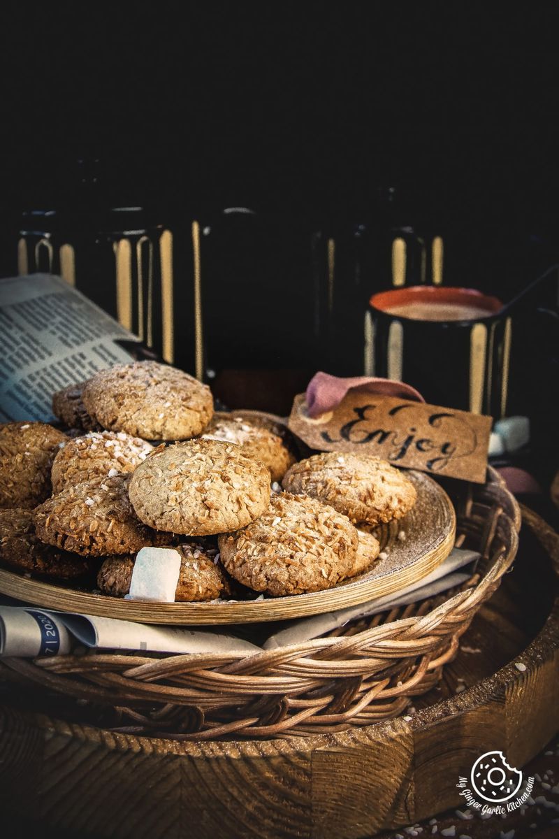 coconut cookies in a plate and black coffee mugs in the background