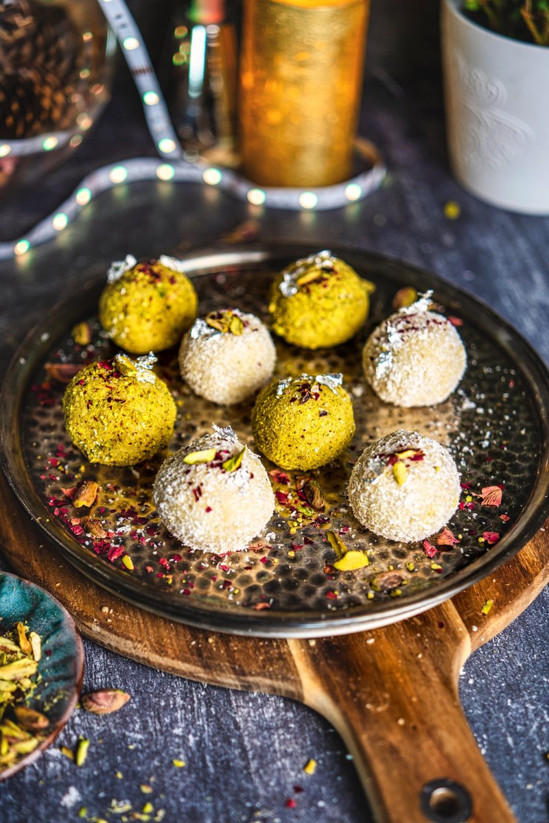 Homemade coconut ladoo truffles in coconut and pistachio coatings, beautifully garnished with rose petals and pistachios for festivals.
