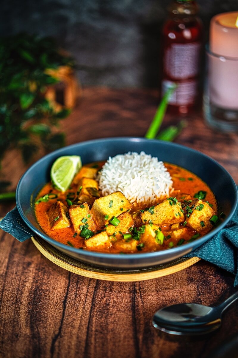 Coconut lime tofu curry served with rice in a bowl, creamy vegan curry with golden tofu cubes and fresh lime wedge