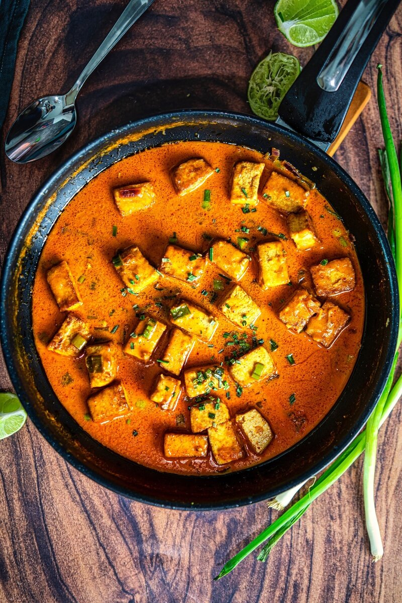Coconut lime tofu curry cooking in pan, crispy tofu cubes simmering in thick coconut curry sauce