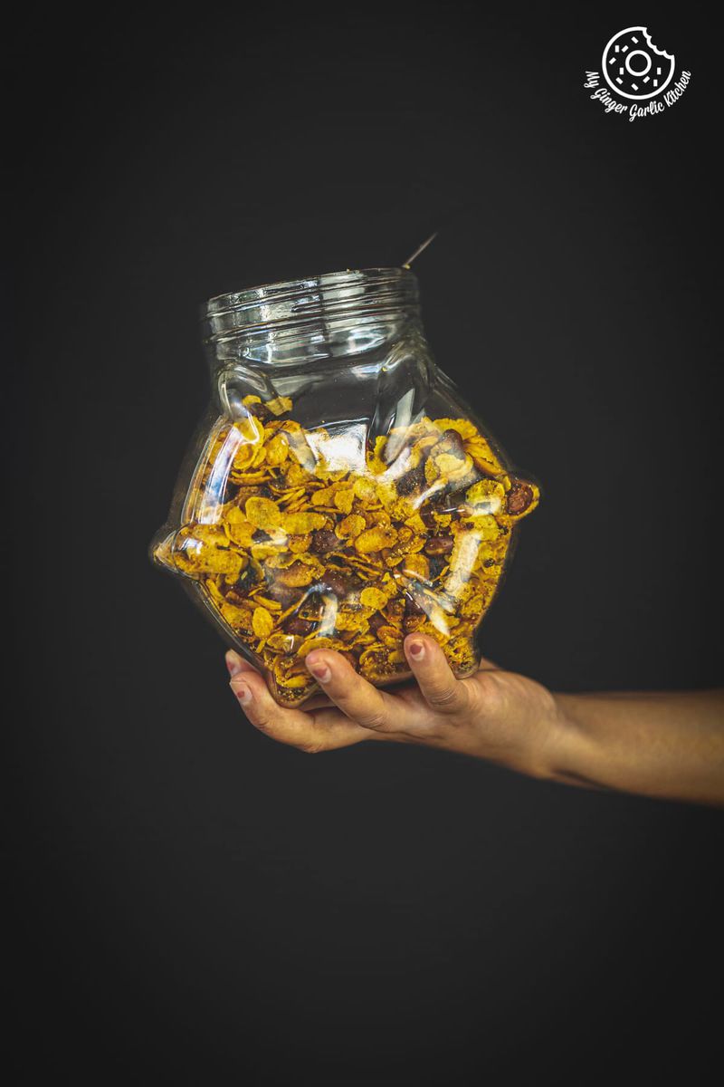 a hand holding a jar of roasted cornflakes chivda namkeen
