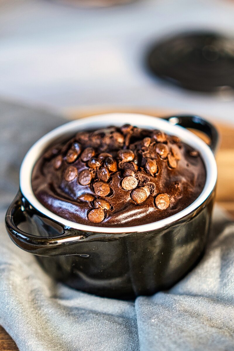 Cottage cheese chocolate mug cake topped with melted dark chocolate chips in a black mug, rich and fudgy high protein dessert