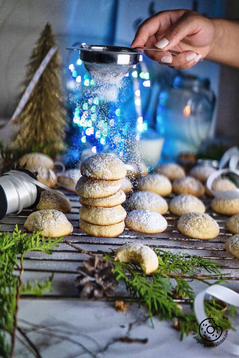a female dusting icing sugar over cream cheese cookies stack
