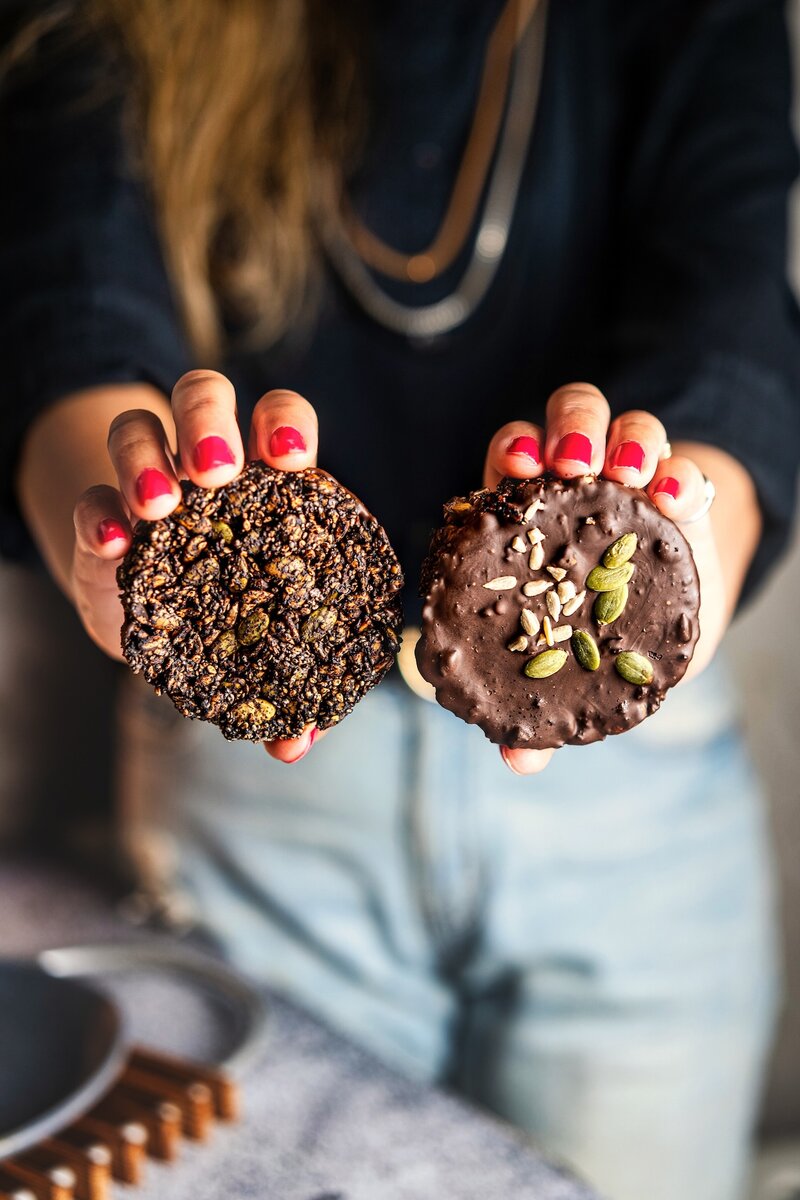Hand-held seed chocolate bites showing baked seed base and dark chocolate coating, healthy make-ahead vegan snack