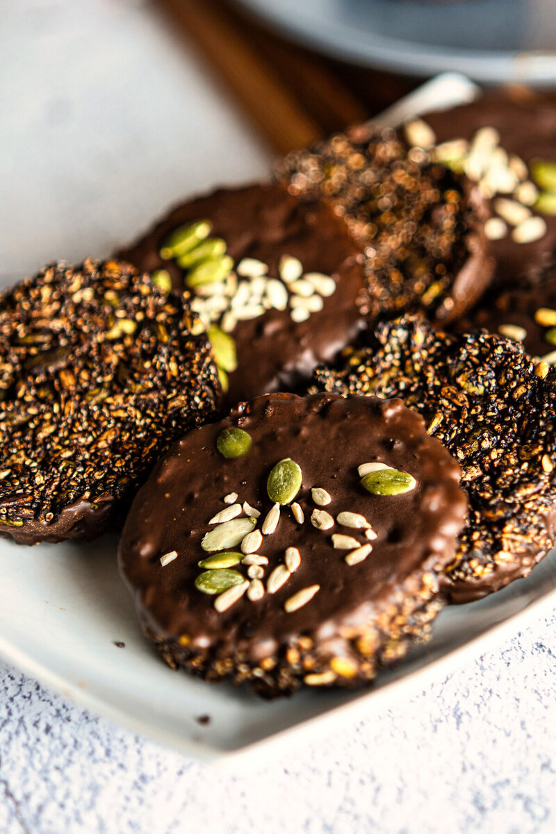 Crunchy seed chocolate clusters on a plate, made with unsweetened cacao, maple syrup, and mixed seeds