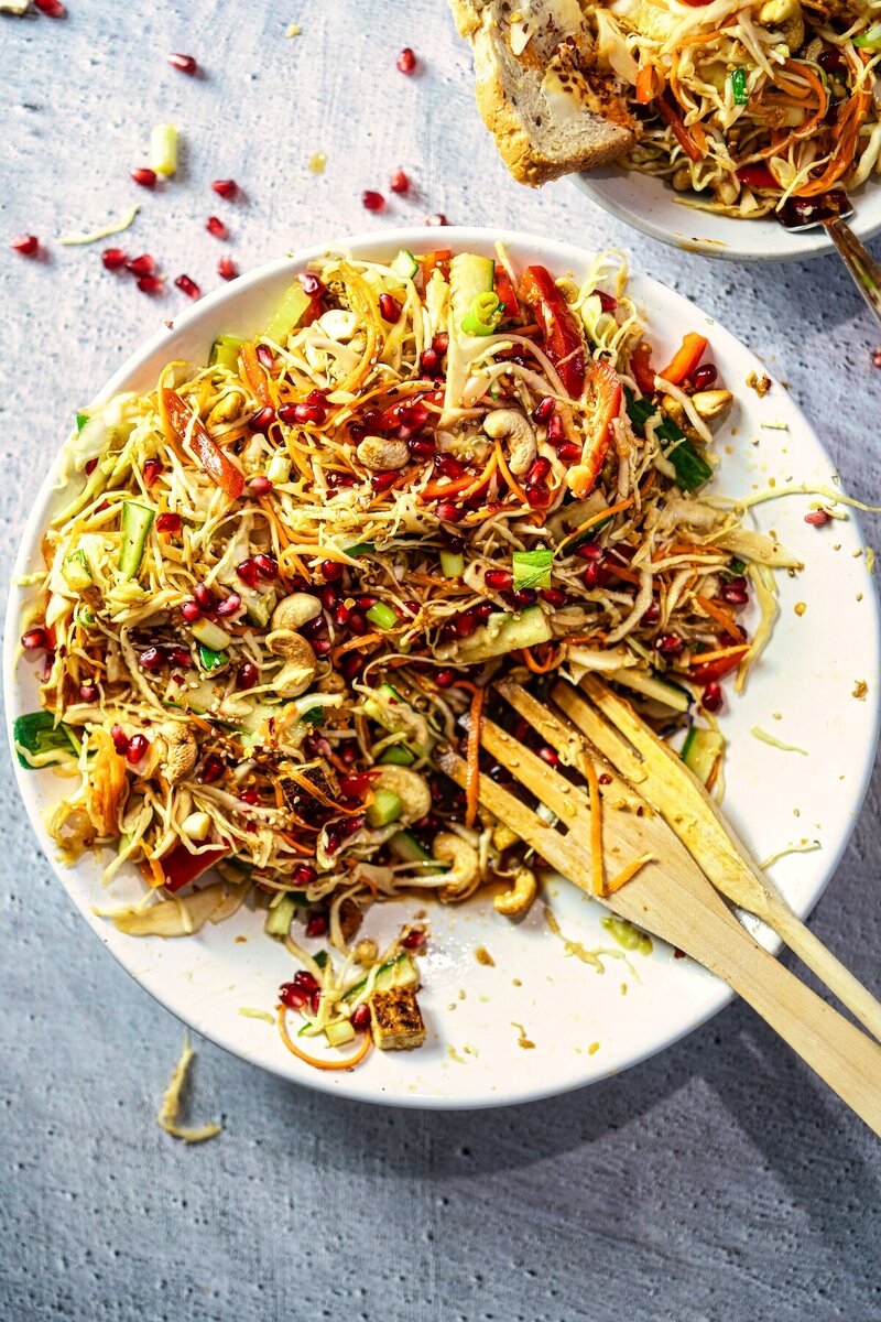 Top view of Asian-inspired crunchy sesame lime cabbage salad with tofu, cashews, and pomegranate arils