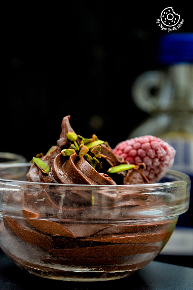 a avocado chocolate mousse in a glass bowl with raspberries