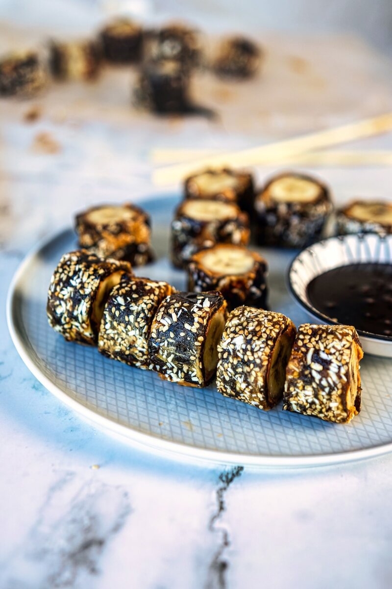 No bake banana sushi with dates coated in sesame seeds on blue serving plate