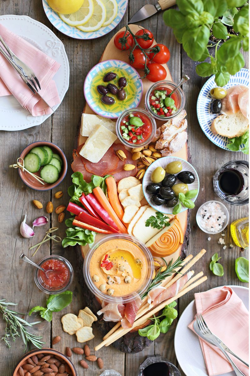 Variety of appetizers including meats, cheeses, and fresh vegetables on a rustic wooden table.