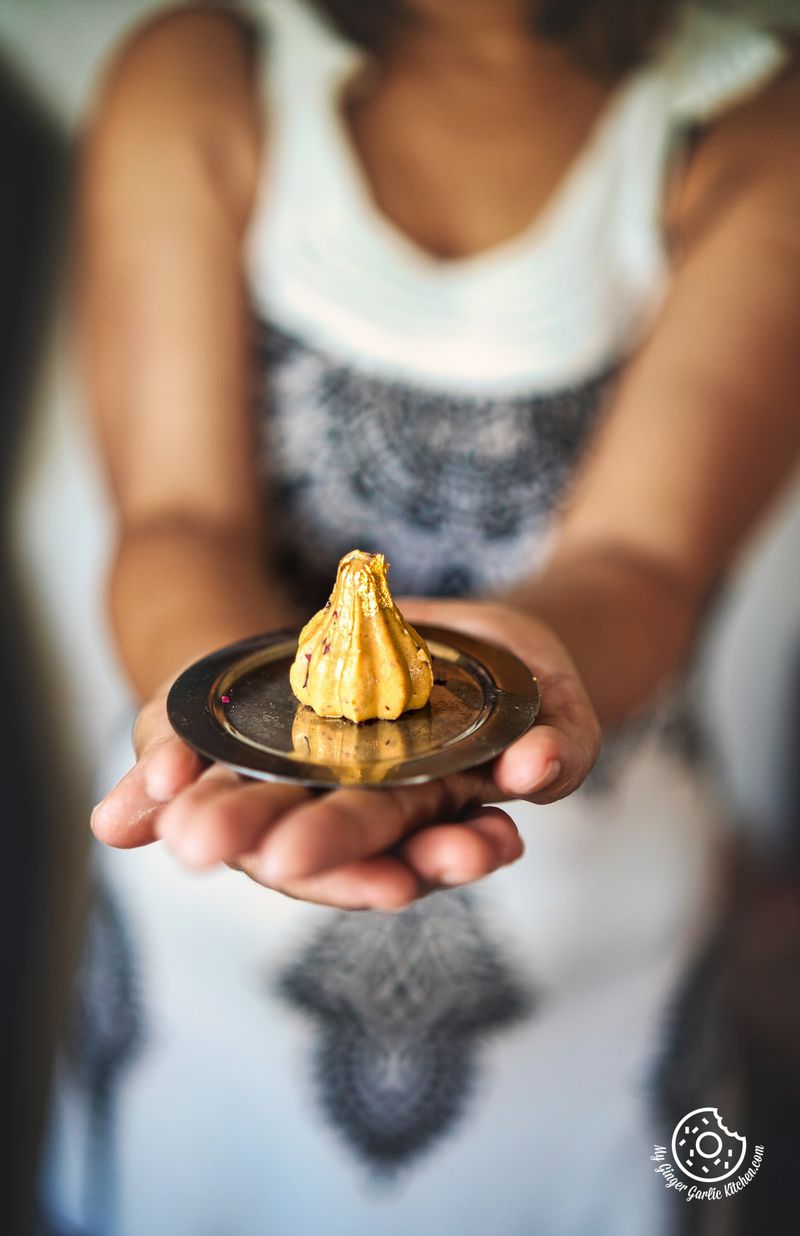photo of a woman holding a plate with a Dulce De Leche Modak on it