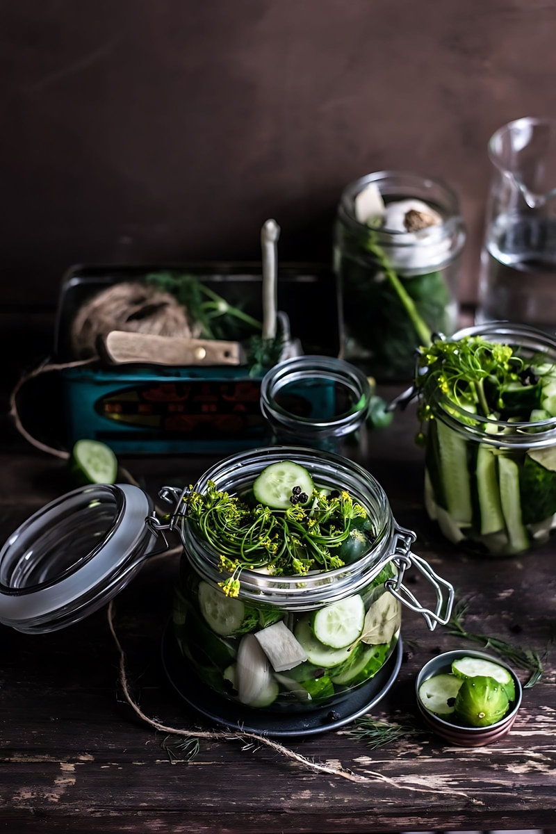 there are many jars of pickles and cucumbers on a table