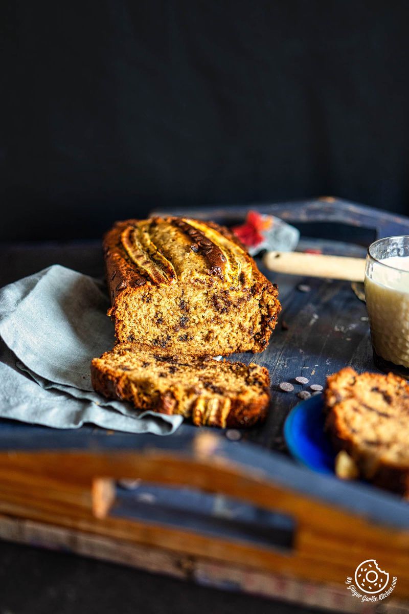 a slice of eggless banana bread on a tray next to a cup of coffee
