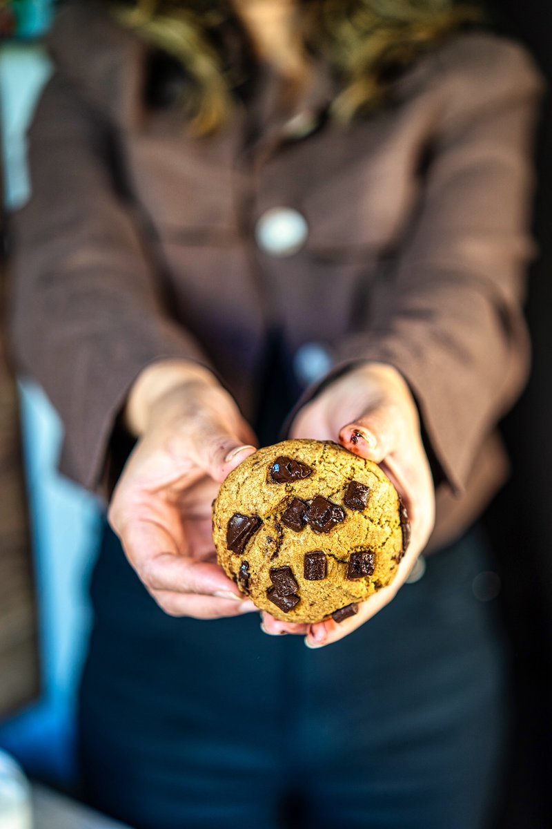 Hand holding a thick eggless brown butter chocolate chip cookie loaded with dark chocolate chunks, soft and chewy homemade bakery-style cookie without eggs
