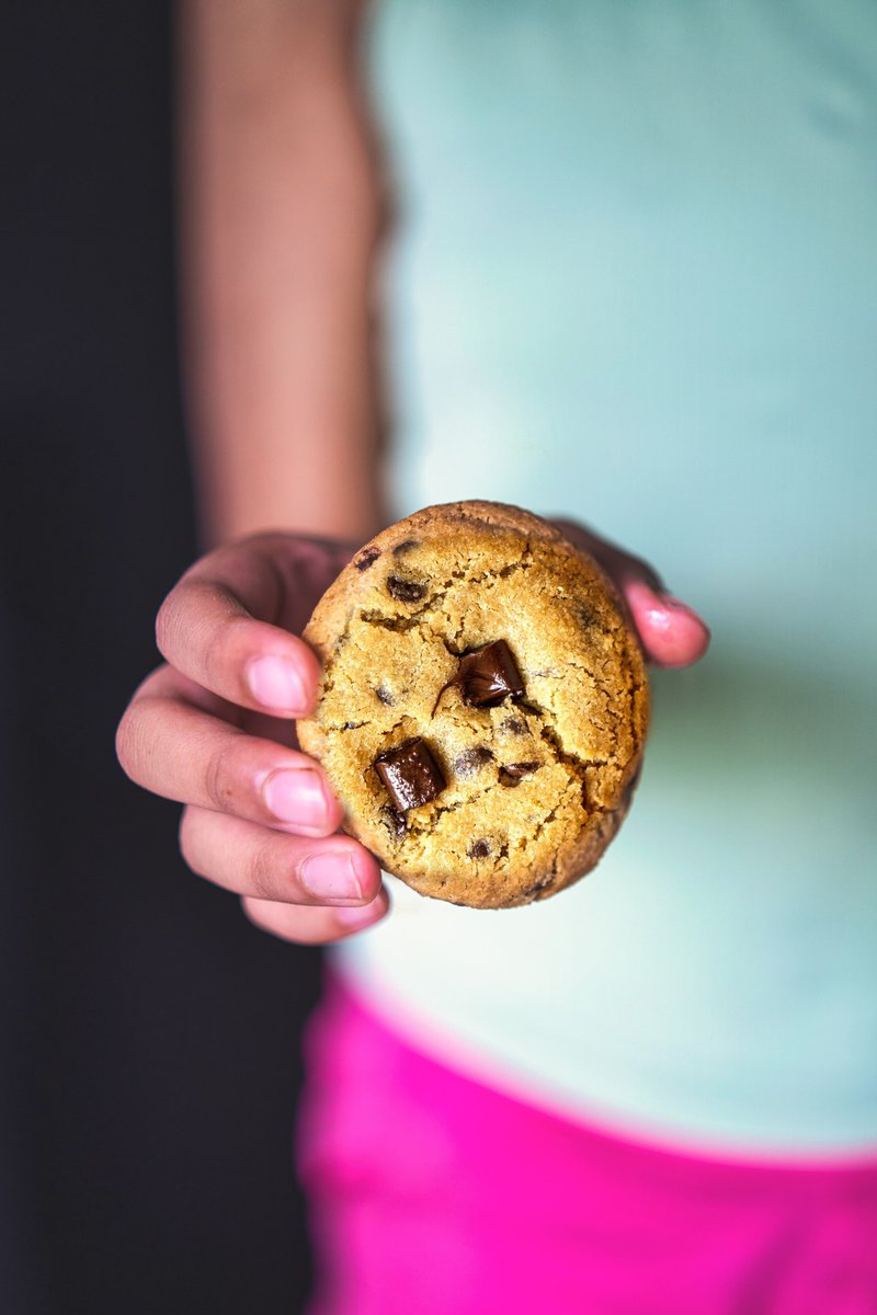 Close-up of a person holding an eggless chocolate chip cookie.